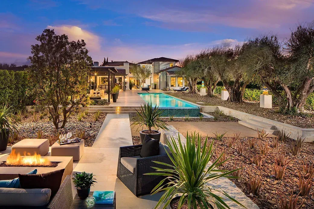 Back garden with a pool and fire pit at dusk
